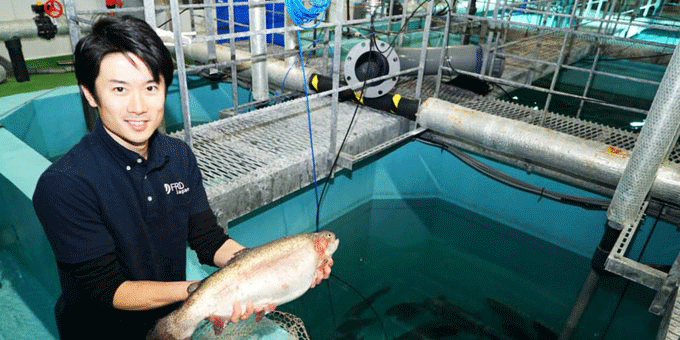 陸上養殖場で育ったサーモンを手に持つ十河様